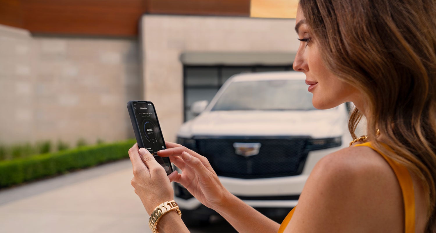 lady checking her mobile with a Cadillac vehicle background | Steinle GMC Cadillac in Fremont OH
