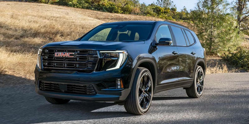GMC Acadia SUV driving on scenic road with modern styling